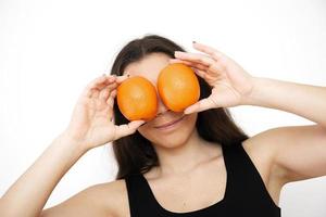 Beautiful young woman brunette holds oranges in front of her eyes photo