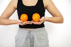 Mujer sosteniendo dos naranjas frente a sus senos, concepto de concienciación sobre el cáncer de mama foto