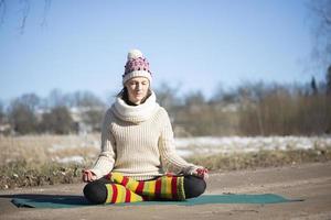 A young athletic woman performs yoga and meditation exercises outdoors photo