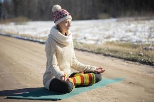 A young athletic woman performs yoga and meditation exercises outdoors