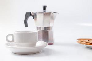 Taza de café con leche y cafetera espresso sobre fondo blanco. foto