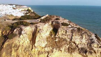 Vista panorámica de la playa paradisíaca, acantilados y camino cuesta abajo en carvoeiro - toma de revelación panorámica aérea video