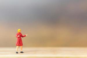 Miniature person standing on a wooden background photo