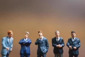 Miniature businessmen standing on a wooden background, business leader and teamwork concept photo