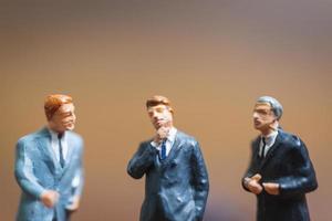 Miniature businessmen standing on a wooden background, business leader and teamwork concept photo