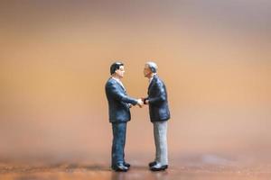 Miniature businessmen standing on a wooden background, business leader and teamwork concept photo