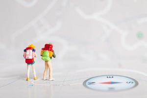 Miniature travelers with backpacks walking on a map, travel and adventure concept photo