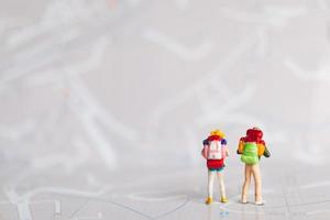 Miniature travelers with backpacks walking on a map, travel and adventure concept photo
