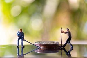 Trabajadores en miniatura sosteniendo herramientas en monedas con un fondo verde bokeh, concepto de construcción foto