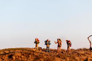 Viajeros en miniatura con mochilas de montañismo, senderismo y mochilero concepto al aire libre foto