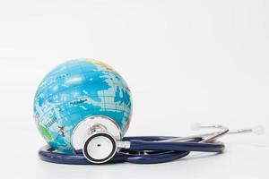 Stethoscope wrapped around a globe on a white background., save the world concept photo