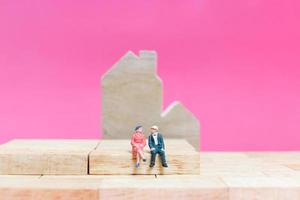 Miniature couple with houses on a pink background, Valentine's Day concept photo