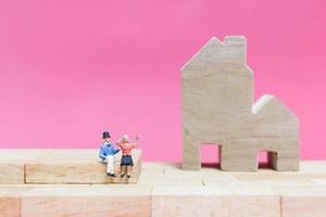 Miniature couple with houses on a pink background, Valentine's Day concept photo