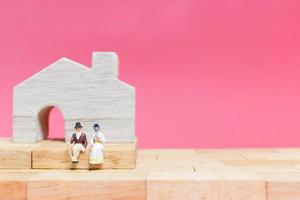 Miniature couple with houses on a pink background, Valentine's Day concept photo