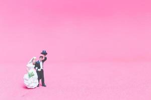 Miniature wedding, a bride and groom on a pink background photo