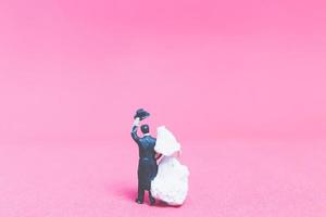 Boda en miniatura, una novia y el novio sobre un fondo de color rosa foto