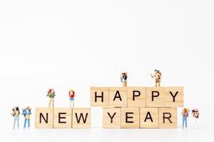 Miniature people on wooden blocks with the text Happy New Year on a white background photo