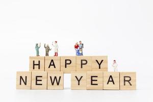 Miniature families on wooden blocks with the text Happy New Year on a white background photo