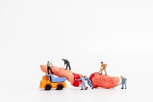 Miniature workers teaming up to create Halloween party props on a white background photo