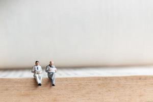 Miniature businessmen reading a book on an old book, business education concept photo