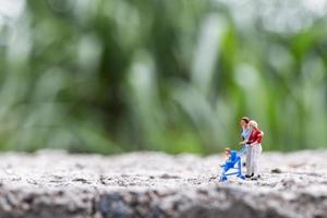 Miniature parents with children walking outdoors, happy family concept photo