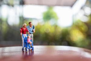 Miniature parents with children walking outdoors, happy family concept photo