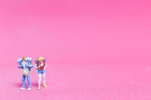 Miniature couple of travelers on a pink background