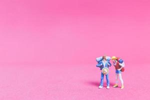 Miniature couple of travelers on a pink background photo