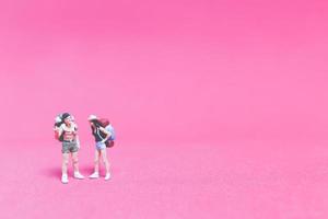 Miniature couple of travelers on a pink background photo