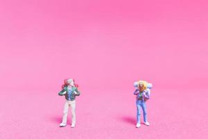 Miniature couple of travelers on a pink background photo