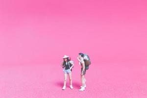 Miniature couple of travelers on a pink background photo