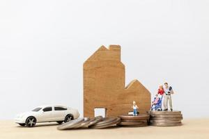 Miniature parents and children with a house and a stack of coins, happy family concept