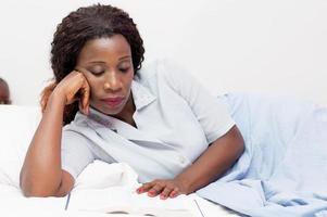 Young woman reading a book in bed photo