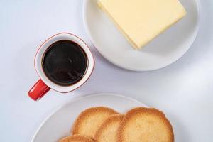 Taza de café roja con galletas sobre fondo blanco. foto