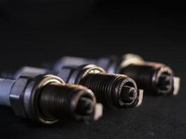 A close-up of a car's faulty spark plugs against a black background photo