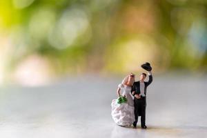 La novia y el novio en miniatura al aire libre con un fondo verde bokeh foto