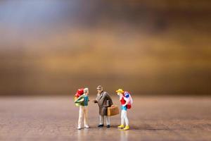 Miniature travelers standing on a wooden background, travel concept photo