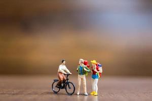 Miniature travelers standing on a wooden background, travel concept photo