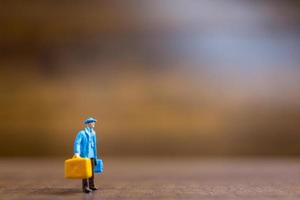 Miniature travelers standing on a wooden background, travel concept photo