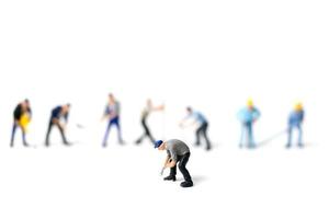 Miniature workers holding tools on a white background, construction concept photo