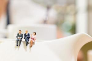 Miniature businesspeople sitting on a teacup