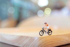 Miniature person cycling on a wooden bridge, health care concept photo