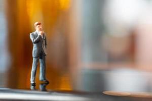 Miniature businessman standing and thinking with a colorful background photo