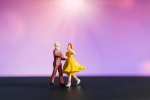 Pareja en miniatura bailando con un colorido fondo bokeh foto