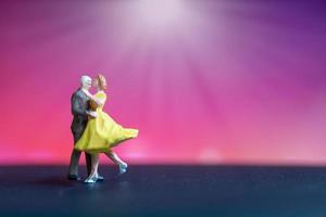 Pareja en miniatura bailando con un colorido fondo bokeh foto