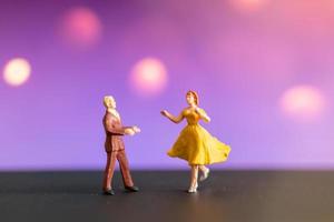 Miniature couple dancing with a colorful bokeh background photo