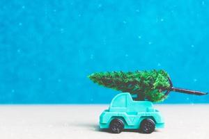 árbol de navidad en un coche en miniatura, concepto de celebración de la temporada navideña foto