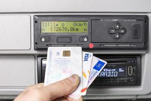 Olomouc, Czech Republic 2021- Hand holding a driver digital card, bank debit card and digital tachograph print out in front of a digital tachograph