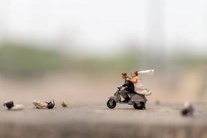 Pareja en miniatura en una motocicleta en un jardín. foto