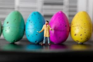 Artista en miniatura sosteniendo un pincel y pintando huevos de pascua para pascua foto